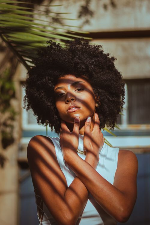 Free Portrait of a woman in a white dress with striking shadows created by natural sunlight. Stock Photo
