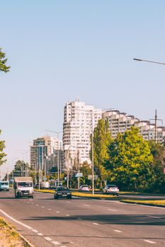 City street view with modern apartment buildings and vehicles on a sunny day.