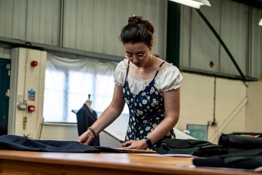 A focused seamstress crafting garments in an indoor textile workshop setting.