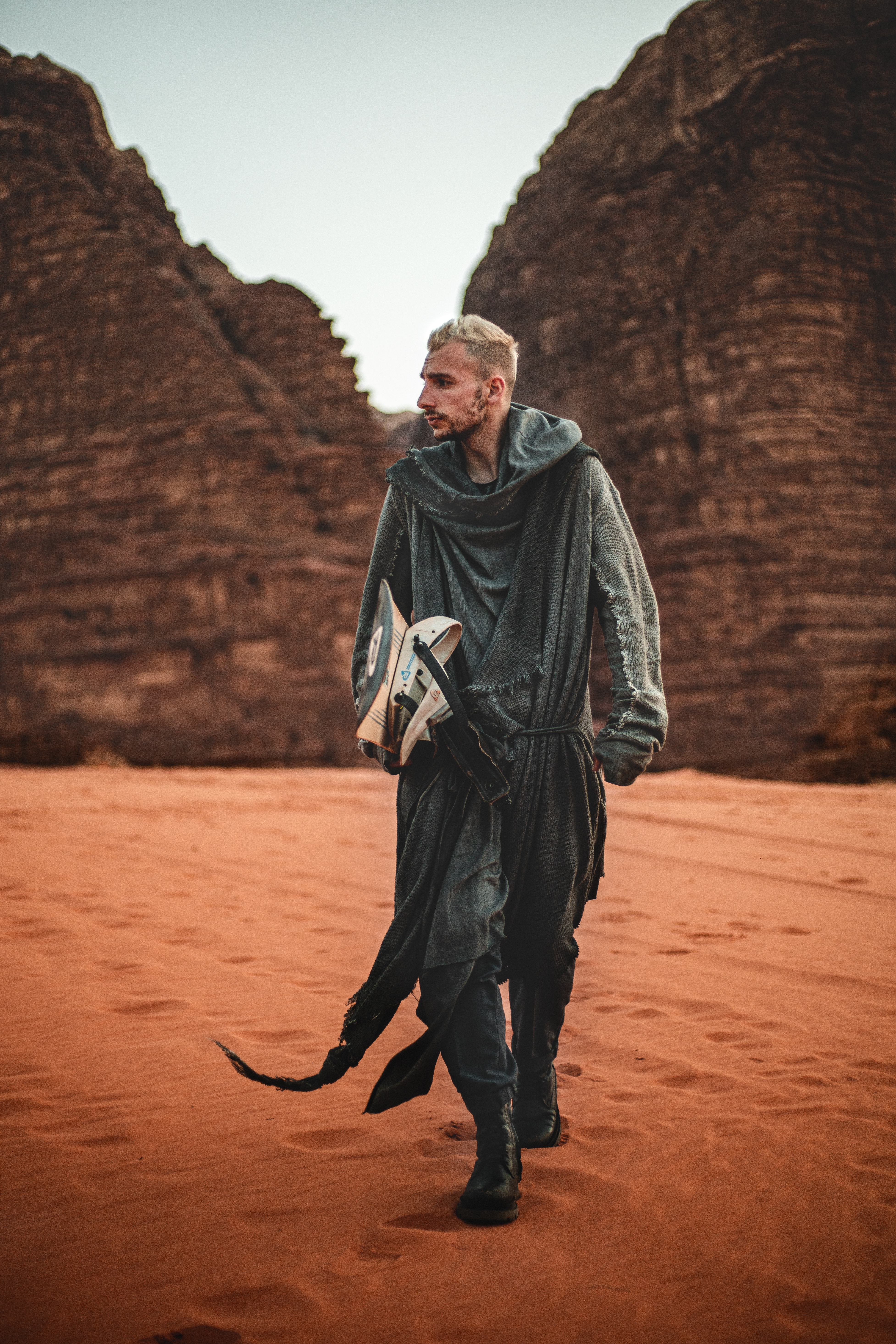 A man in unique attire walks through a red desert canyon, evoking adventure and exploration.