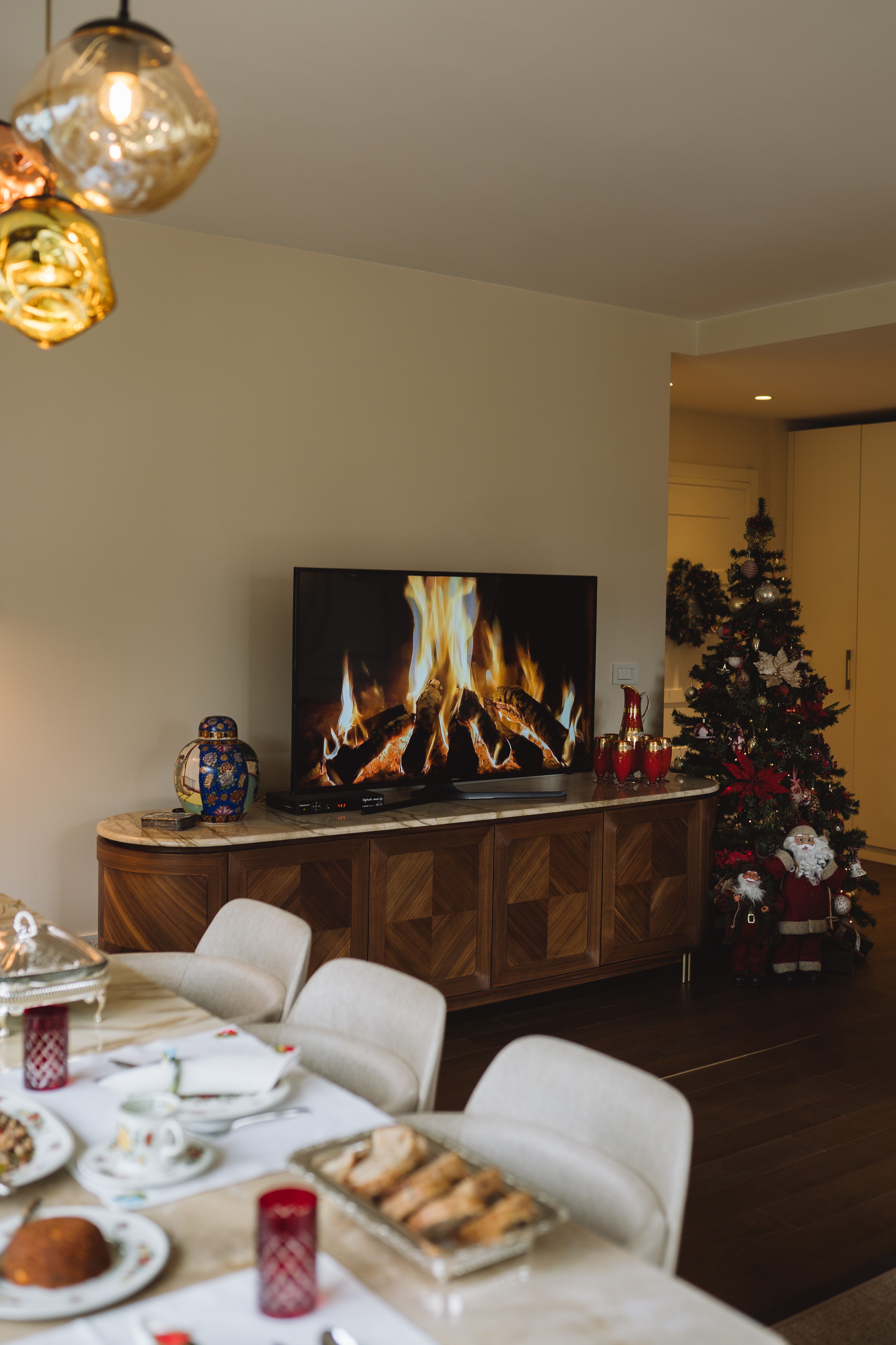 Warm holiday dining room with decorations and cozy fireplace on TV.