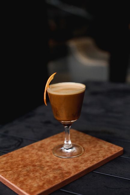 A stylish coffee cocktail with a touch of orange garnish set on a modern surface.