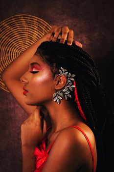 Close-up portrait of a woman with striking makeup and stylish jewelry in a studio setting.
