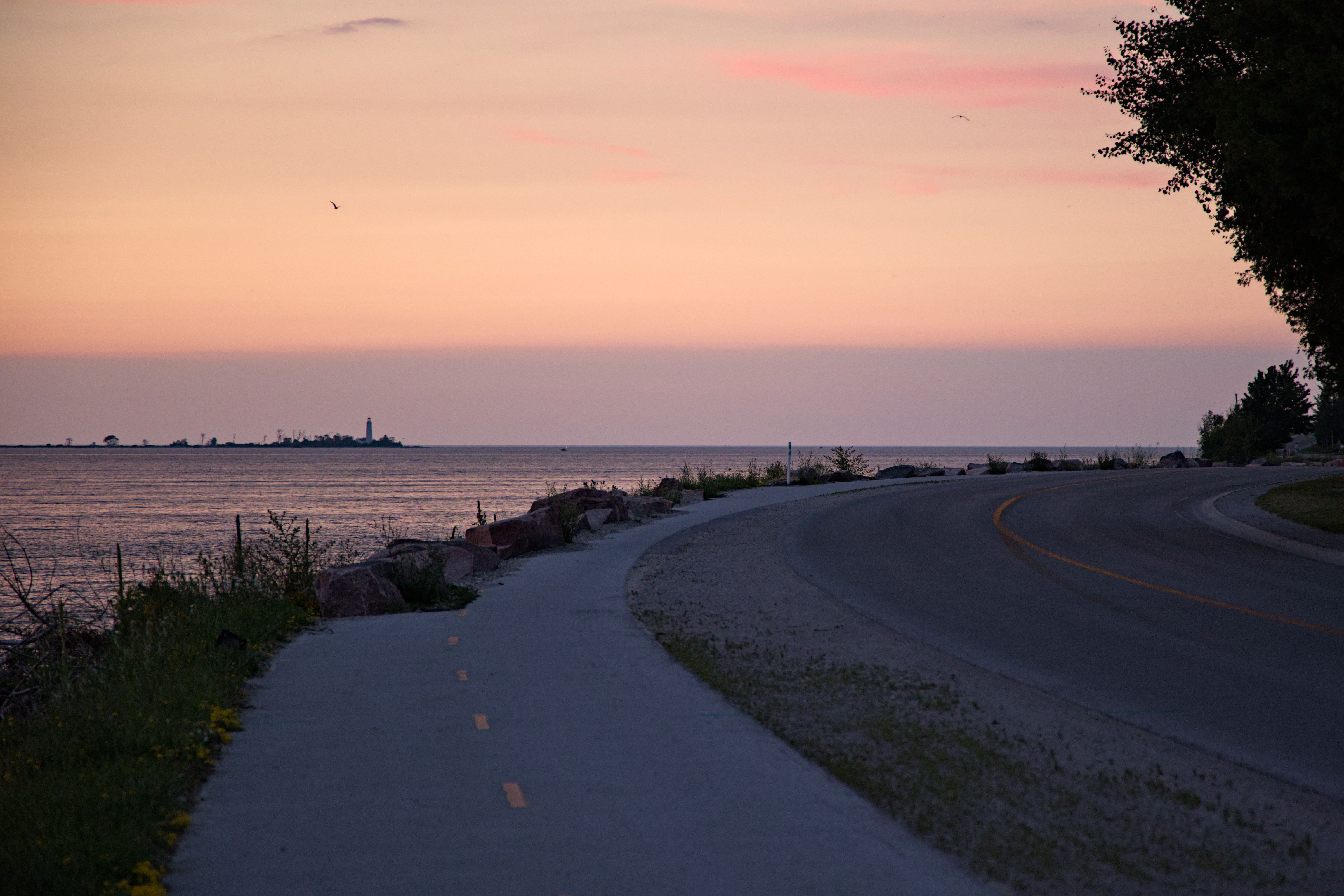 A tranquil sunset over Lake Huron viewed from a coastal road in Ontario, perfect for travel inspiration.