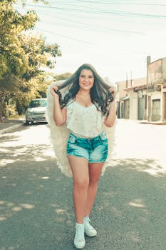 Smiling woman with angel wings poses outdoors on a sunny day, embodying summer vibes.