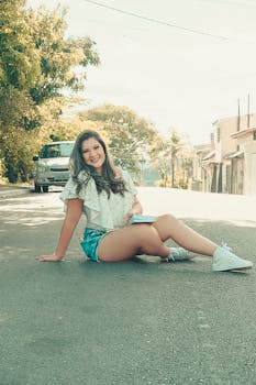 Smiling young woman sitting on a sunny street in São Paulo, enjoying a warm summer day.