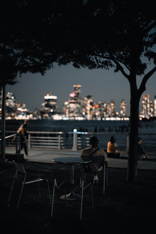 People Sitting on Chair Near Body of Water during Night Time