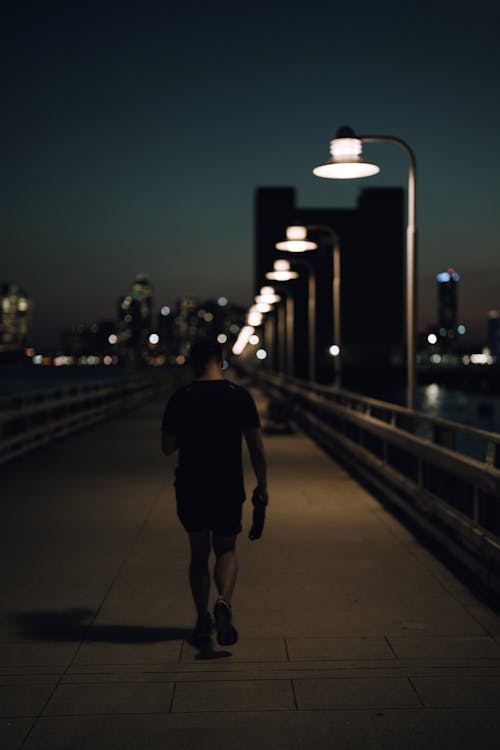 Photo of Man Walking on Sidewalk During Nighttime