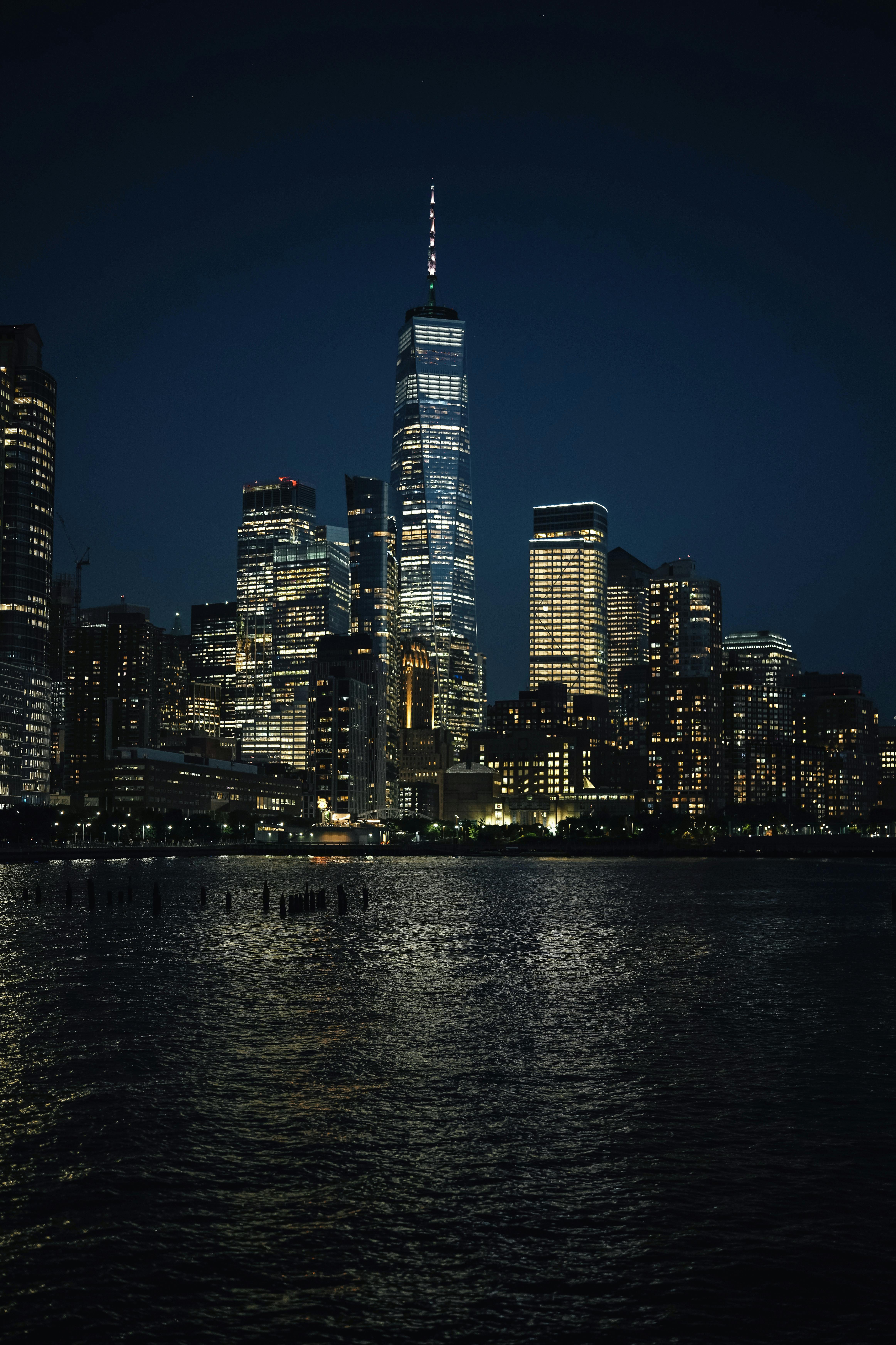 Brightly lit skyscrapers reflecting on the water create a mesmerizing cityscape scene.