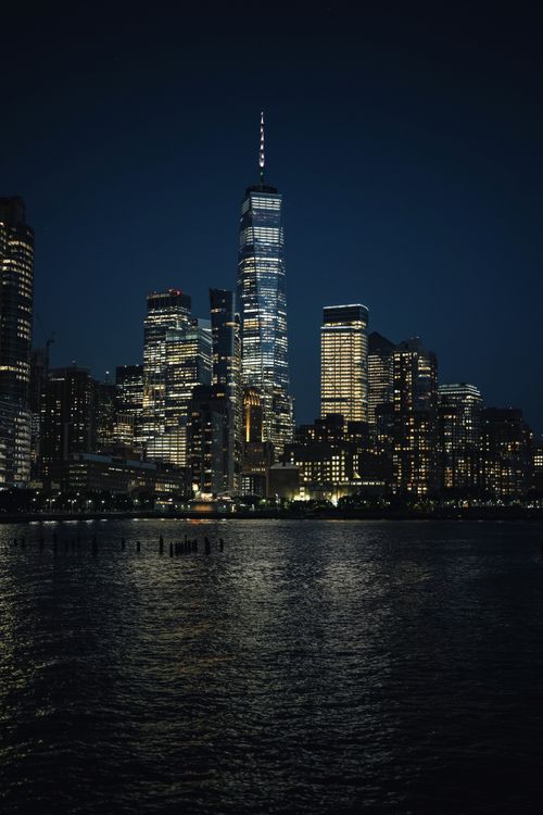 Free Brightly lit skyscrapers reflecting on the water create a mesmerizing cityscape scene. Stock Photo