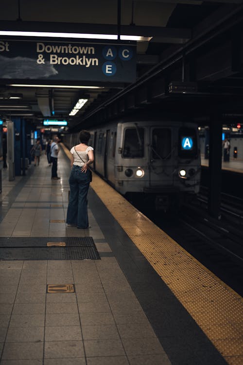 A Person in White T-shirt and Black Pants Standing Beside Train