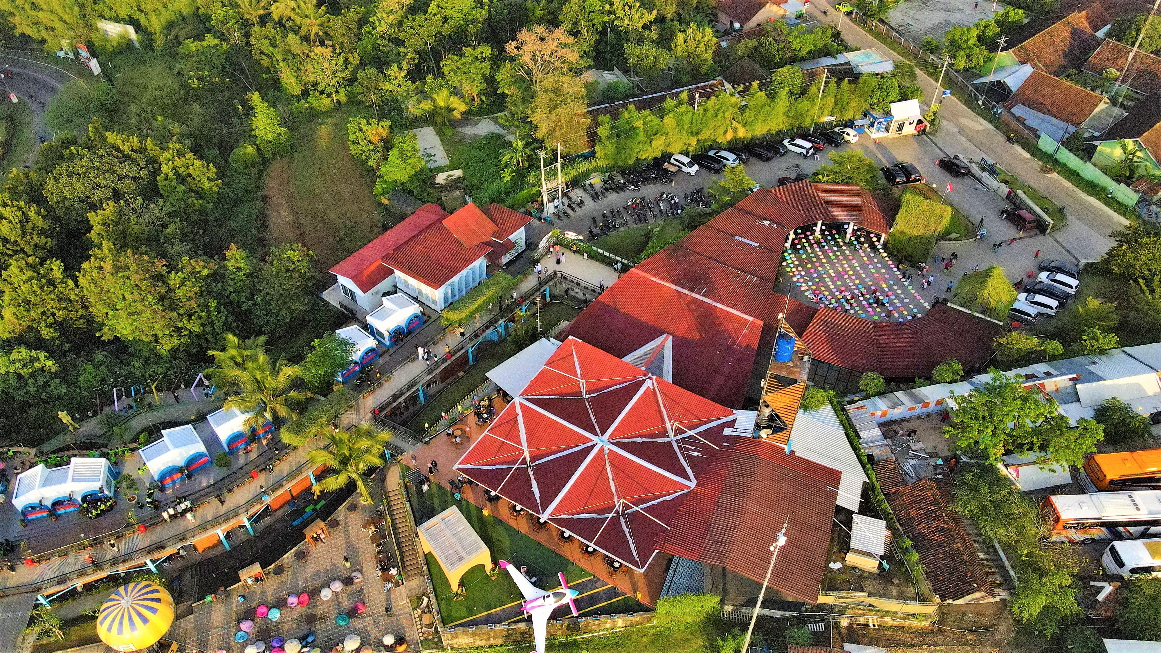 Vibrant aerial view of a tourist site in Yogyakarta, Indonesia, showcasing colorful roofs and lush greenery.