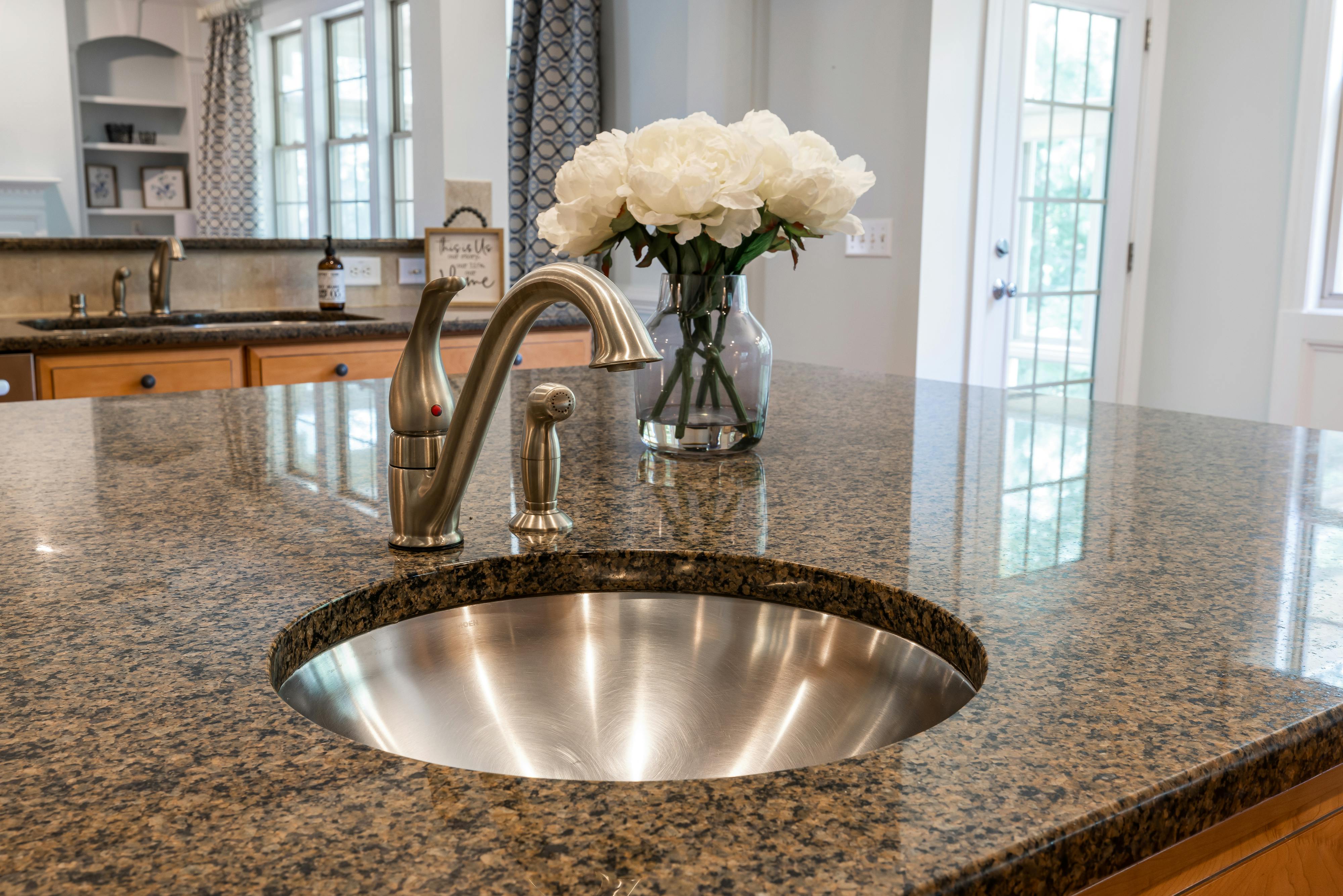 Kitchen with granite countertop, stainless sink, and white peonies
