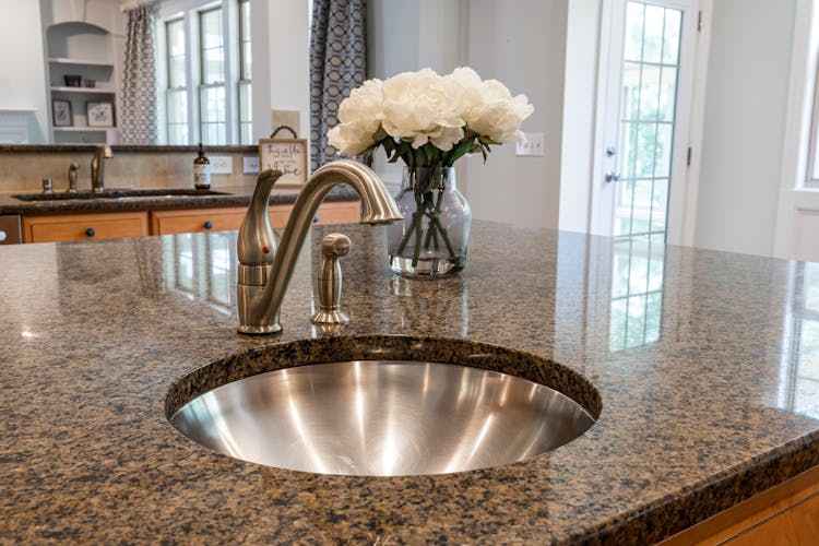 Metal Sink And White Flowers On Stone Worktop 