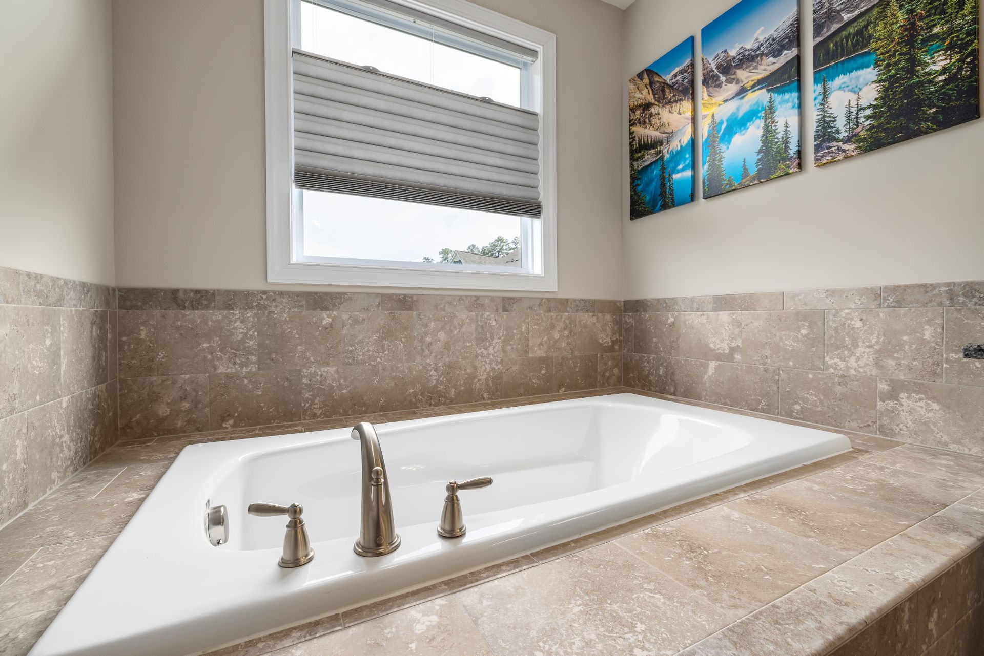 Bright, modern bathroom featuring a luxurious bathtub with a stylish faucet and scenic wall art.