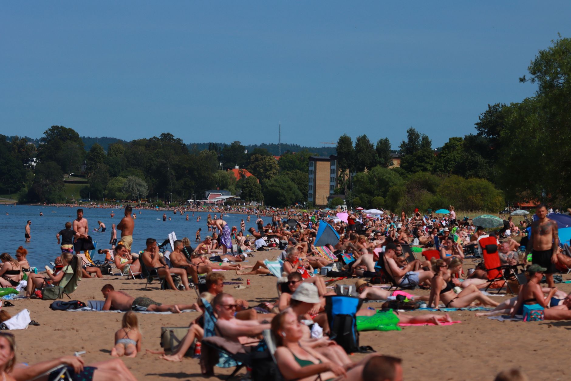 A vibrant summer day at a crowded beach in Jönköping, Sweden, perfect for relaxation and fun.