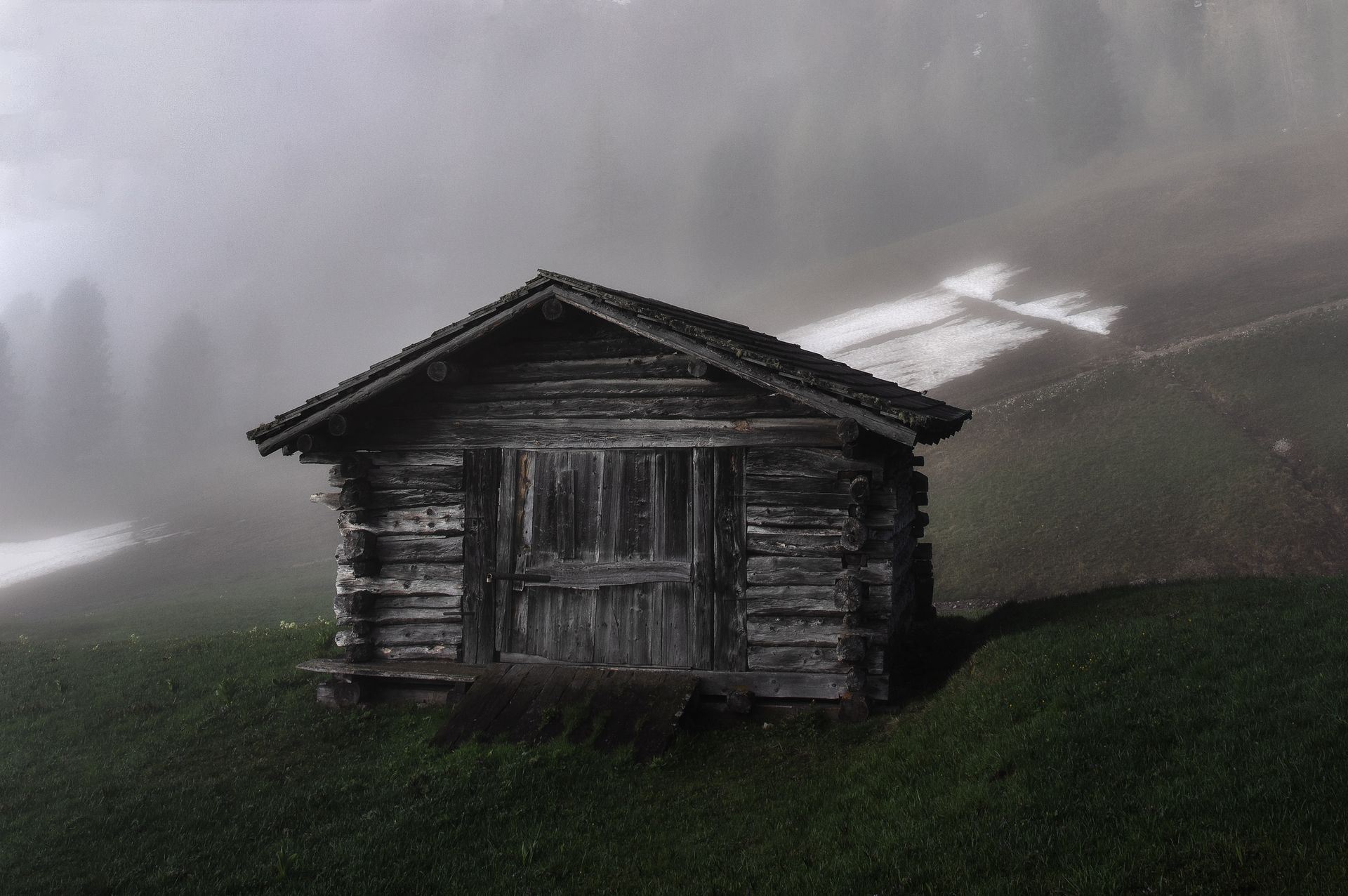 A weathered log cabin standing alone in fog