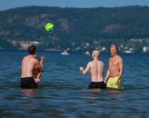 Four men playing volleyball in a lake in Jönköping, Sweden, on a sunny day.