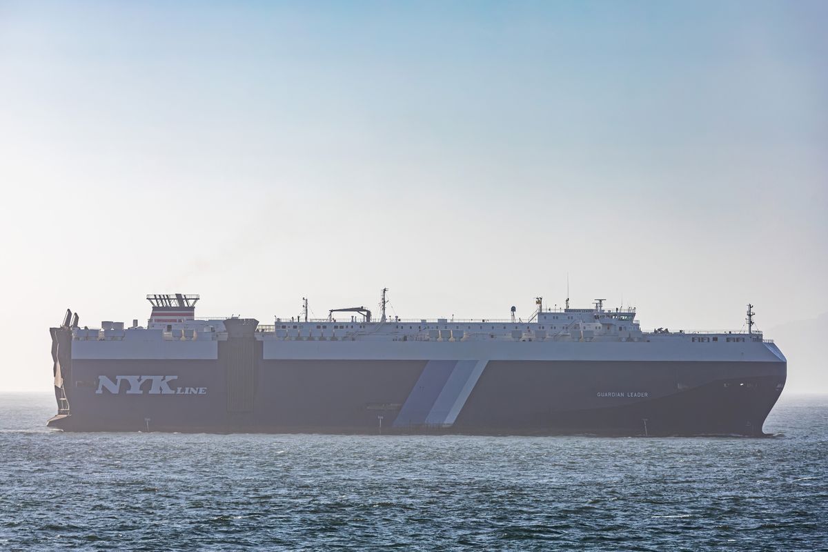 A massive cargo ship traversing the calm sea under a clear sky.