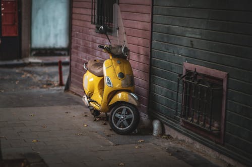 Yellow Motor Scooter Parked Beside Brown Brick Wall