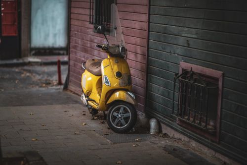 Free A vintage yellow scooter parked against a rustic wall in an Istanbul alley. Stock Photo