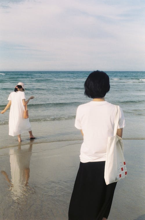 Women Standing on Beach Looking at Sea