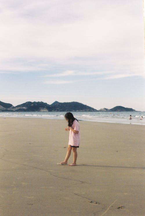A Girl in Pink Shirt Standing on Seashore