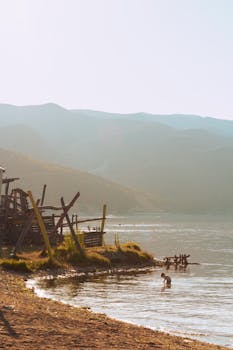 Serene beach scene at sunset in Pogradec, showcasing tranquil waters and distant mountains.
