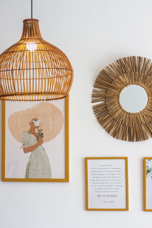 Free Modern wall decor featuring a wicker lamp, framed art, and decorative mirror. Stock Photo
