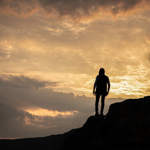 Silhouette of Man Standing on Rock Formation during Sunset