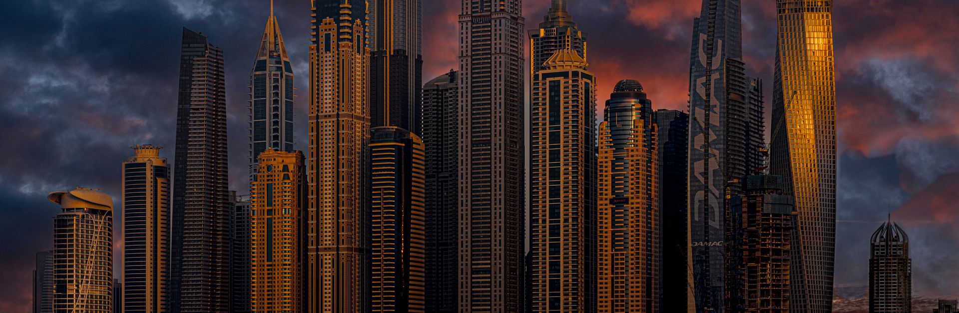 Stunning view of Dubai Marina skyscrapers illuminated by the setting sun with a yacht in the foregro
