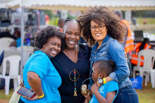 Cheerful friends embracing outdoors at a fun outdoor event.