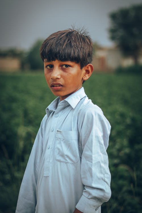 Boy in White Dress Shirt Standing Near Green Grass