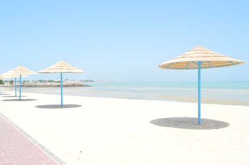 Free Peaceful beach scene with straw sunshades and clear blue water. Stock Photo