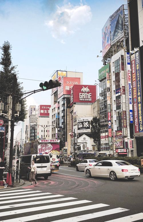 Free Busy Tokyo street scene with traffic, pedestrians, and vibrant neon signs. Stock Photo