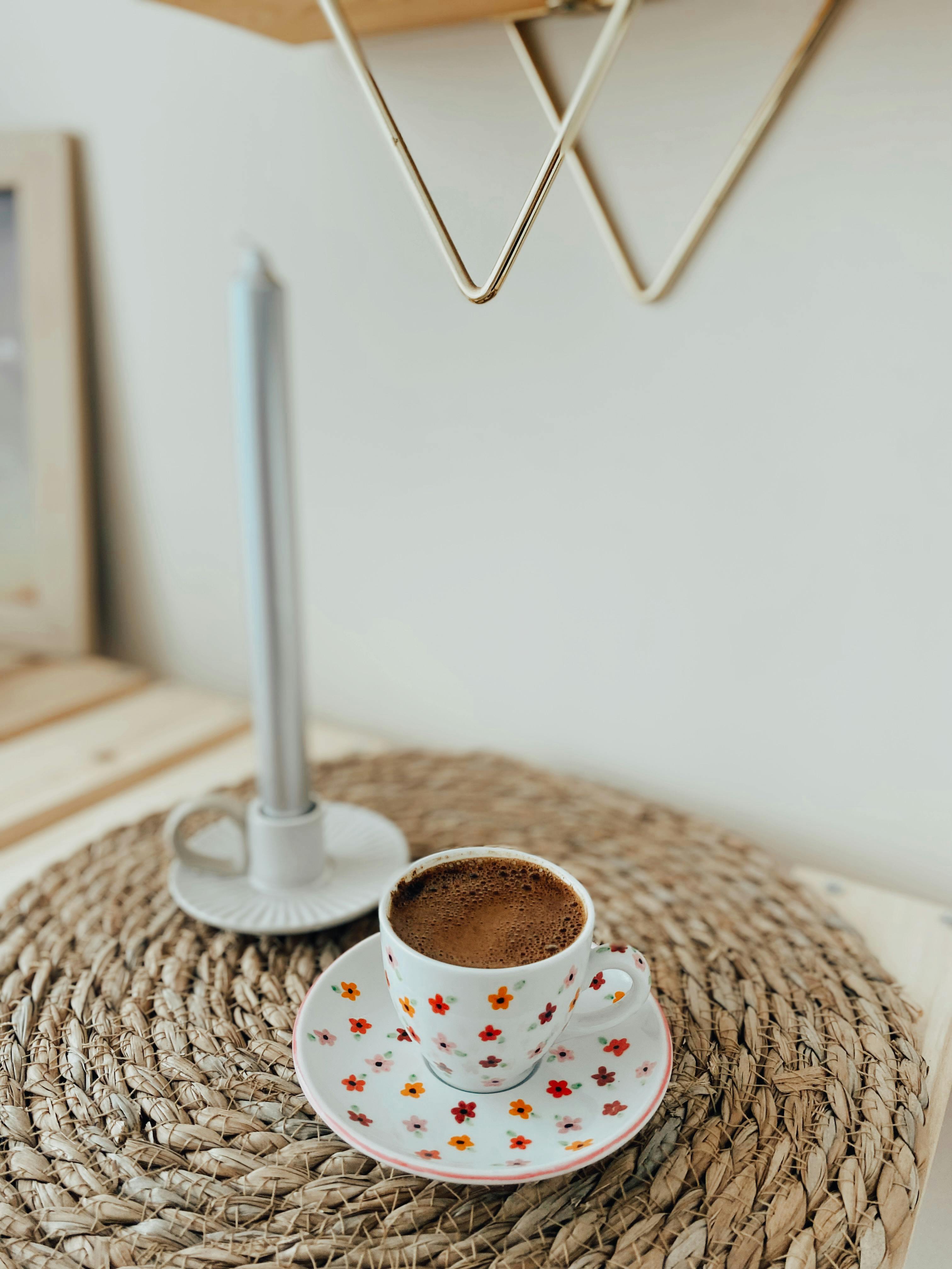 Free Crisp coffee cup and candle on a woven mat creating a cozy ambiance. Stock Photo