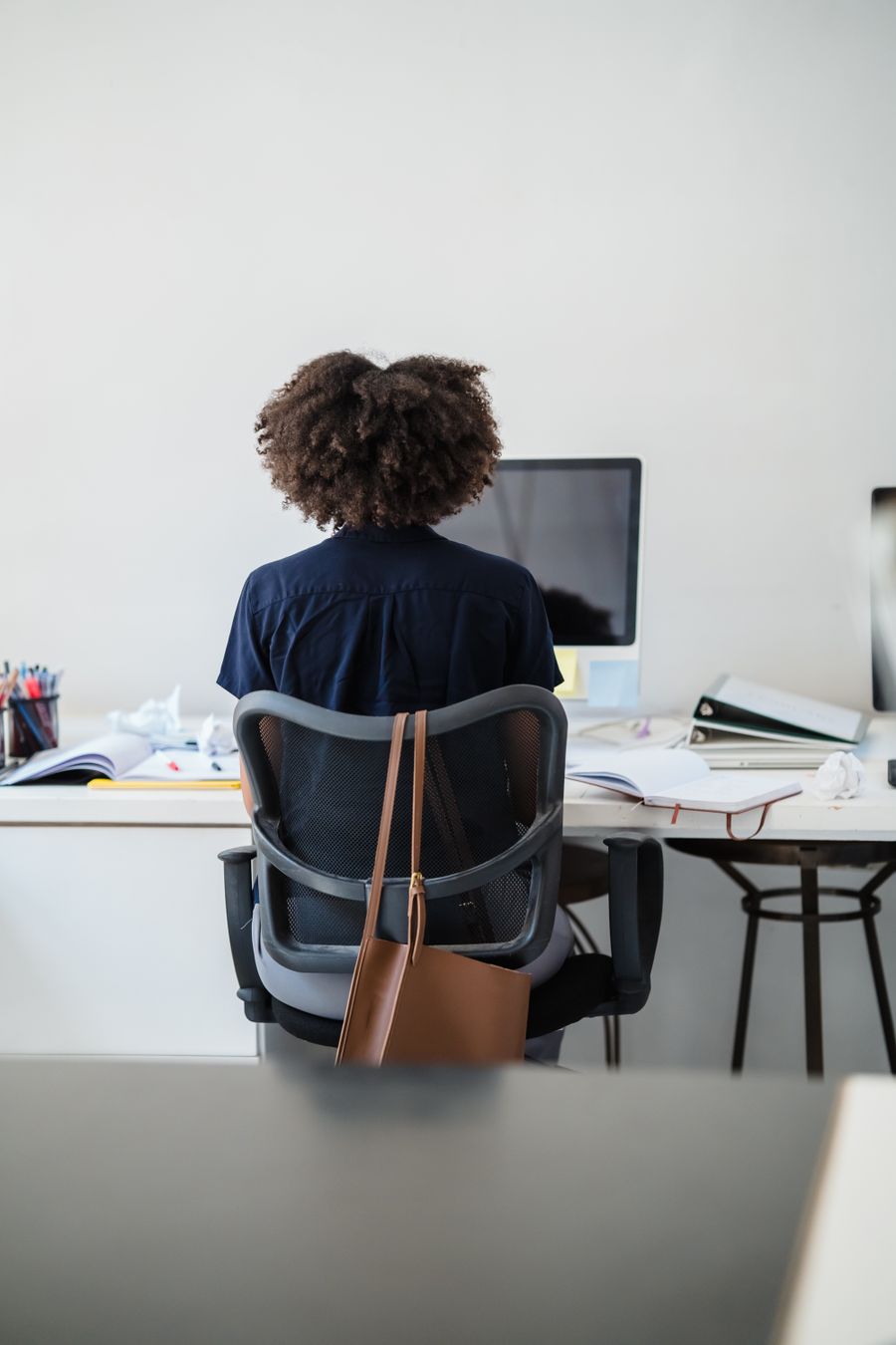 Person working at a desk in an office, seen from behind