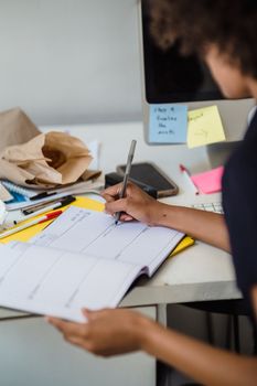 Close-up of a woman writing in a planner at a desk, focusing on organization in a work environment.