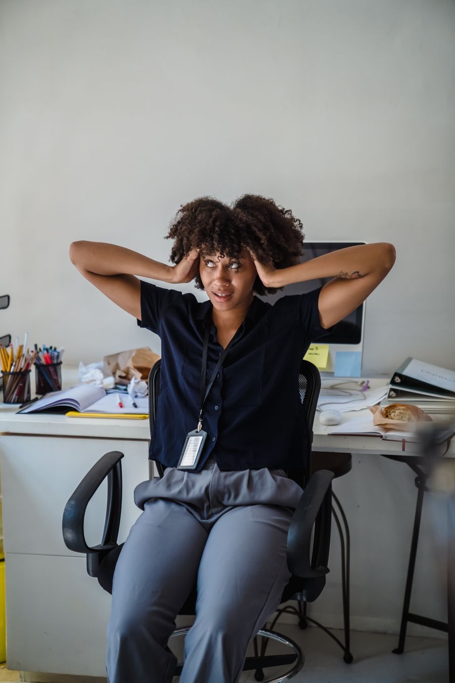 A business owner overwhelmed by paperwork and spreadsheets at her desk