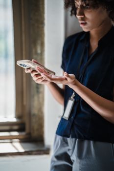 A woman intently uses a smartphone in an office, symbolizing concentration and business multitasking.