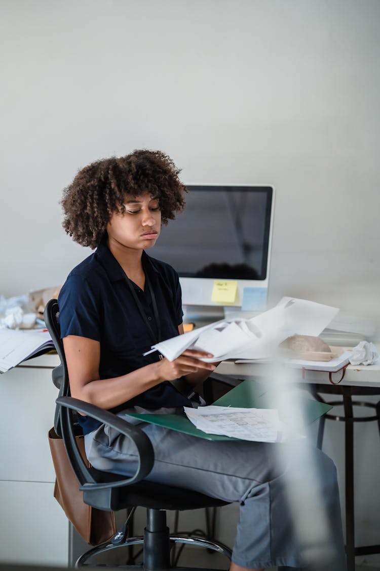 Woman Looking At Documents At An Office Desk