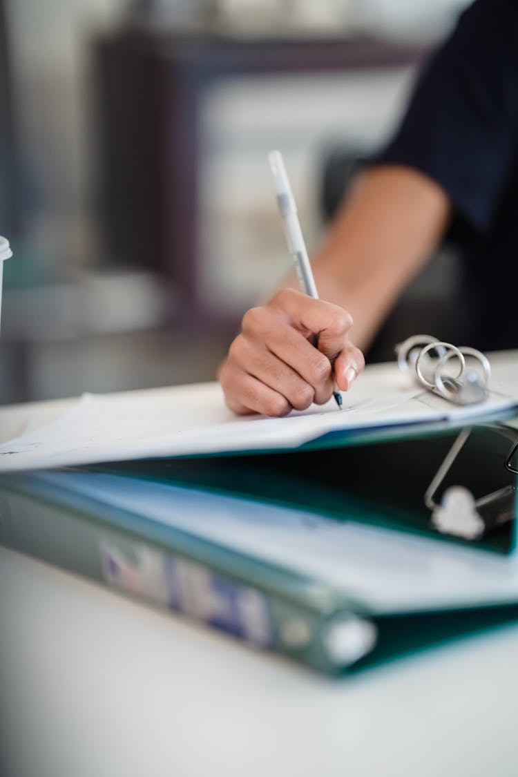 Hand Of Woman Writing On A Document In A Binder