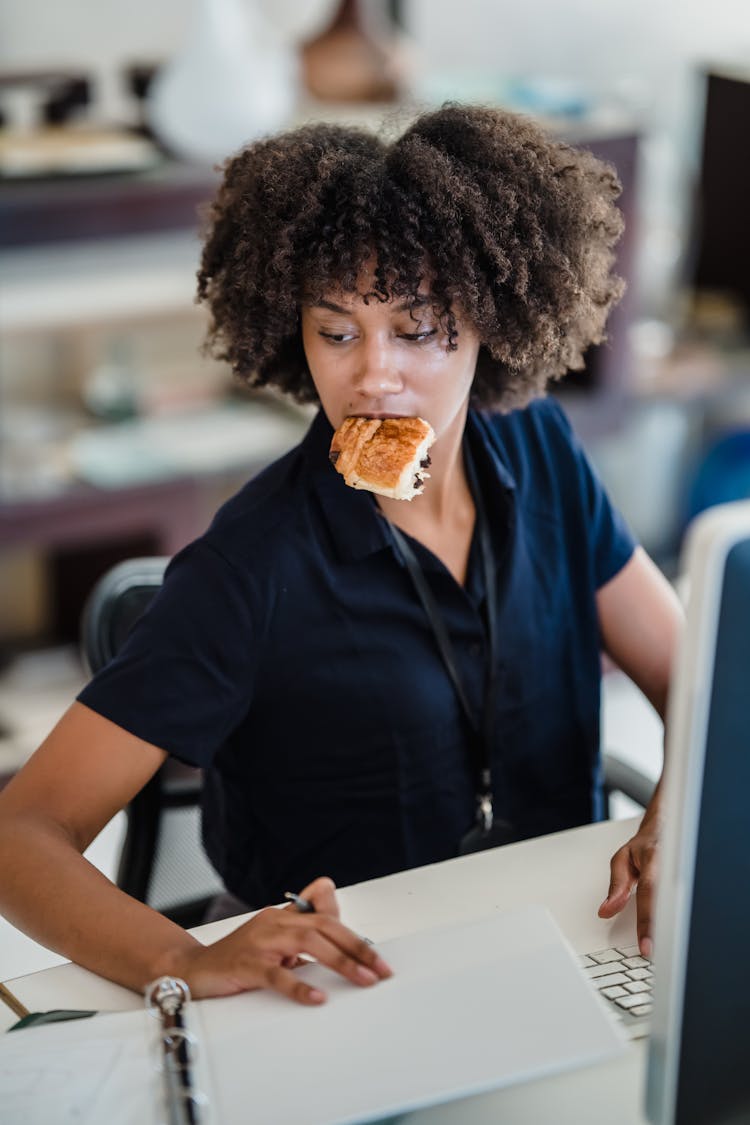 Woman Eating While Working In An Office