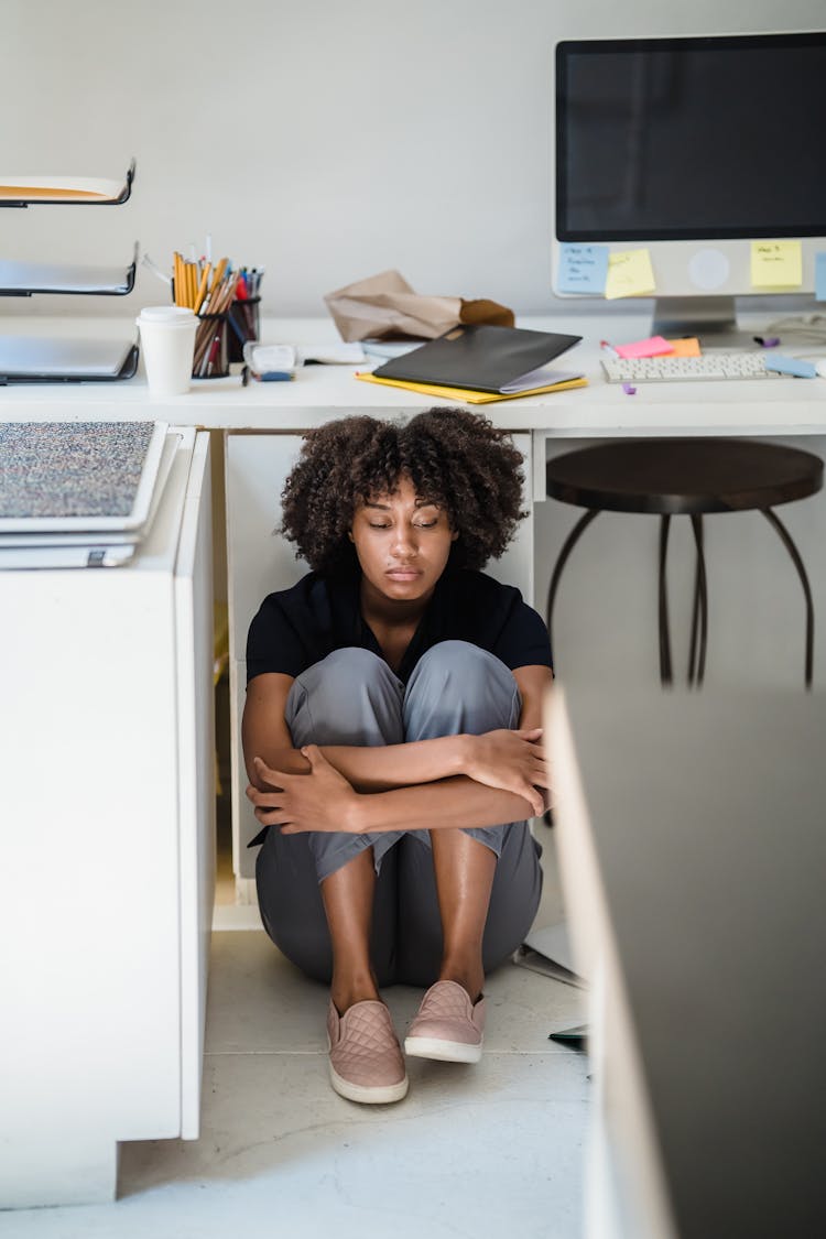 Upset Woman Hiding Under The Desk In Office