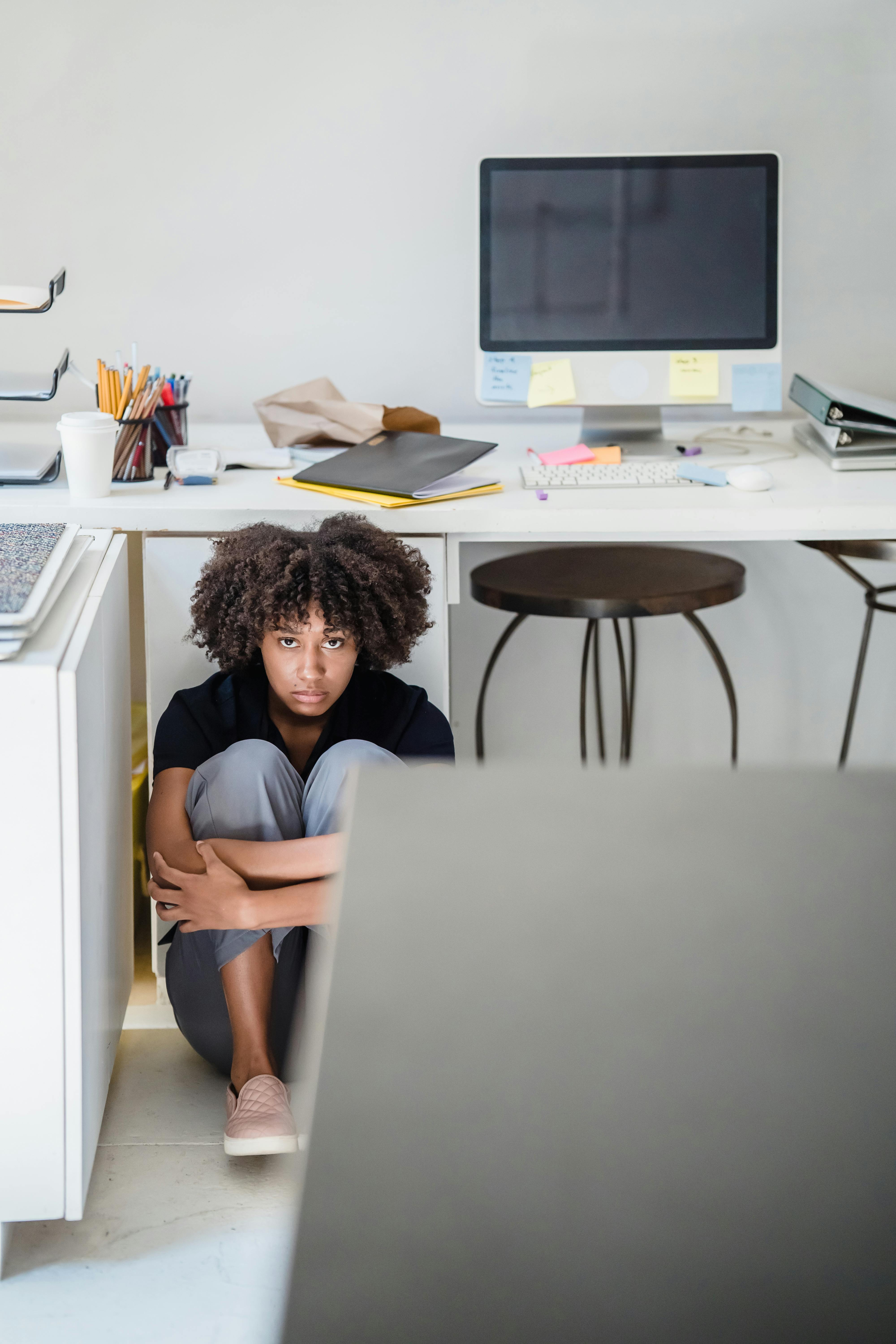 Upset Woman Hiding Under The Desk in Office · Free Stock Photo