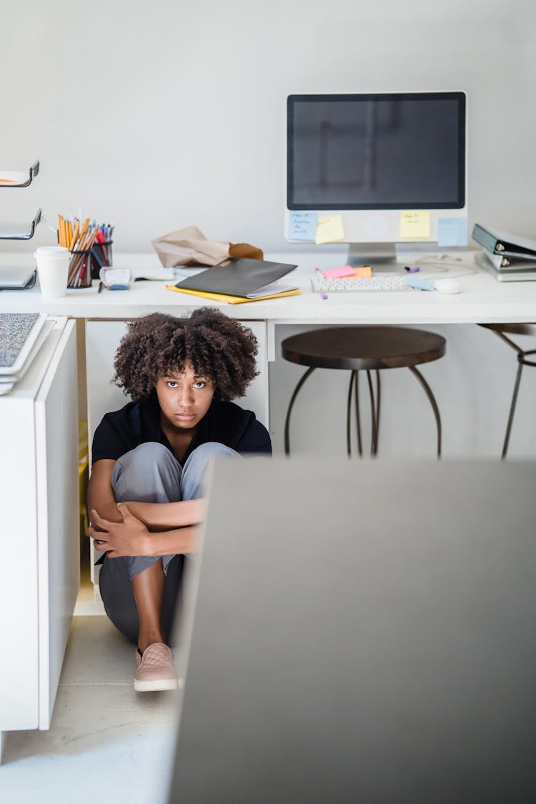 Upset Woman Hiding Under The Desk In Office