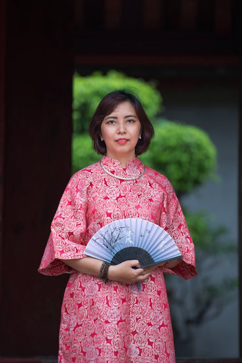 Woman in Red Traditional Dress Holding a Hand Fan