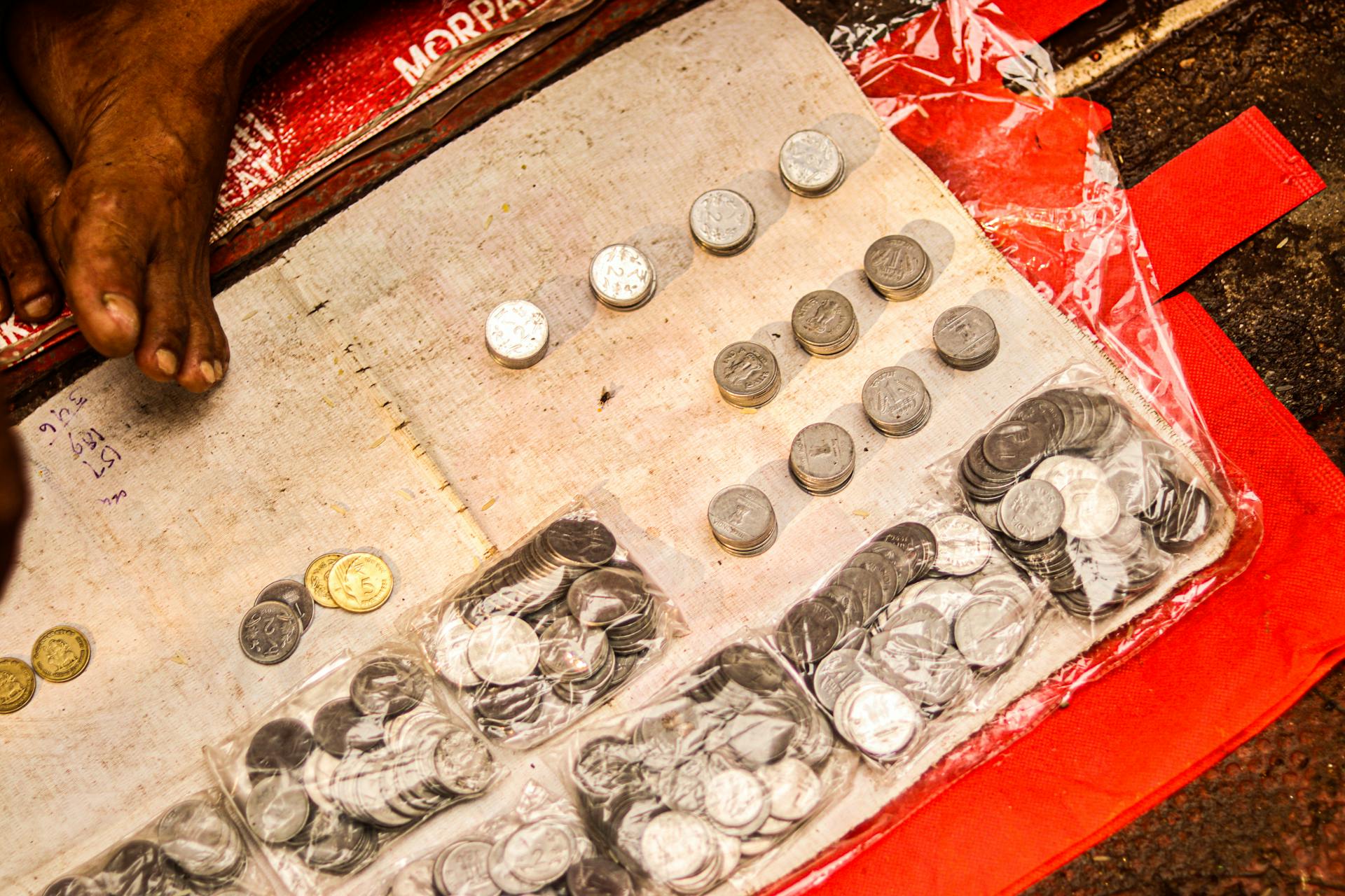 A collection of various coins organized on a red fabric, representing economic transactions.