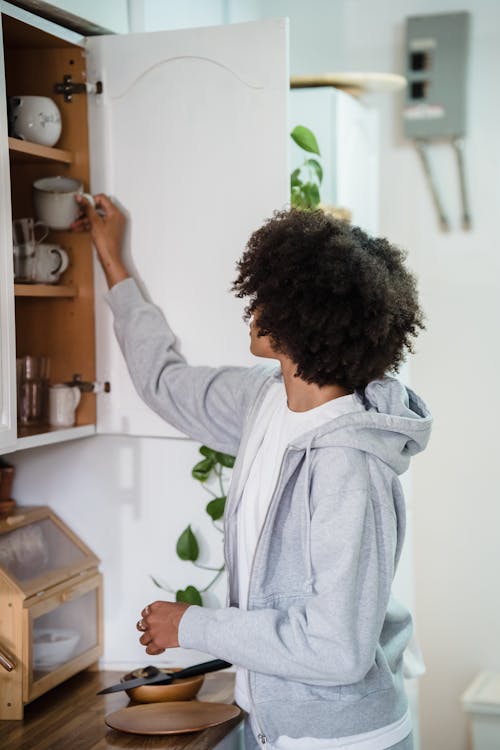 A Woman Taking a Cup from a Kitchen Cabinet