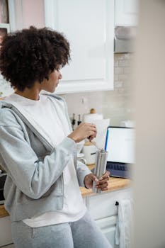 An African American woman grinding coffee in her modern kitchen at home.